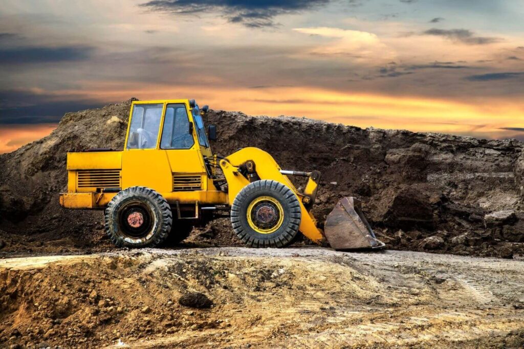 Service vehicle with open compartment displaying tools, parked near a large grader for on-site machinery maintenance.