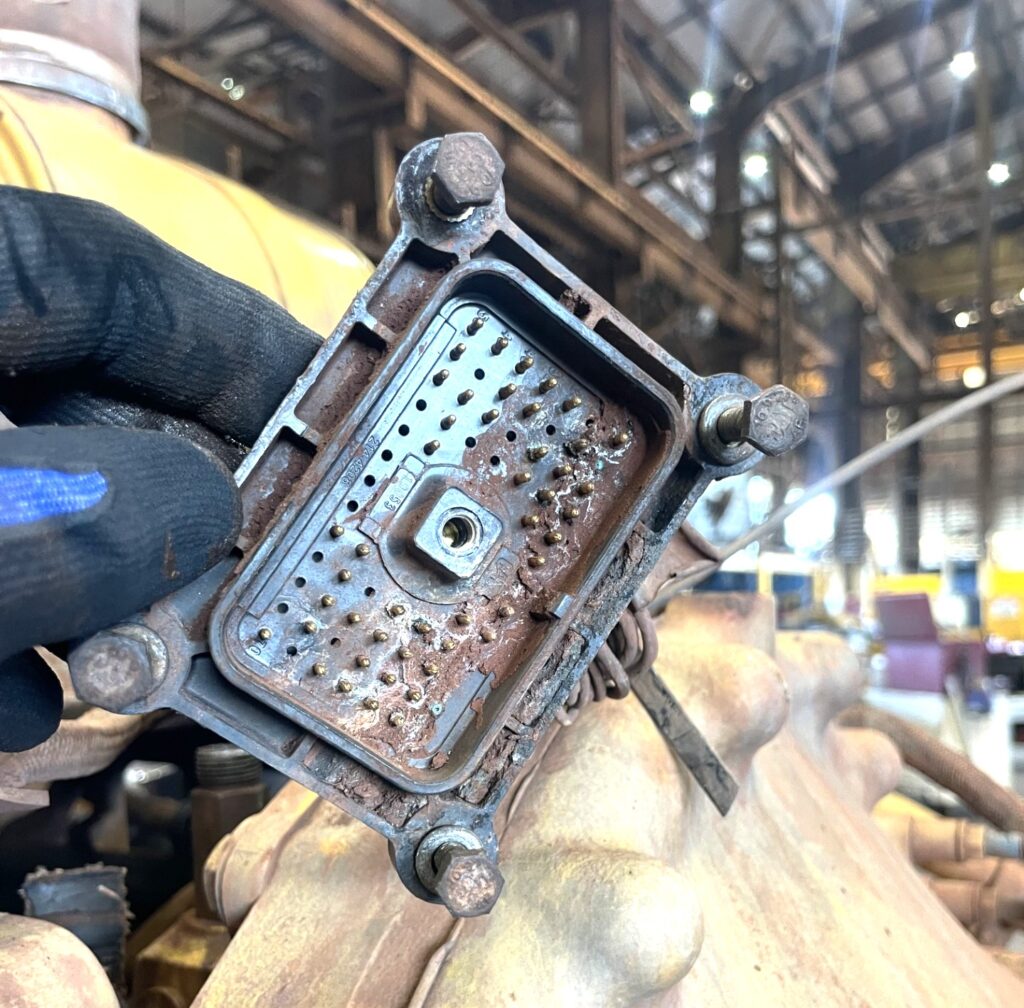 Engine control module showing corrosion and damaged connectors.